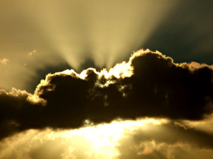 sun rays & storm clouds: golden sun rays spreading from behind dark storm clouds