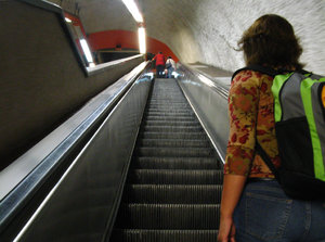Subway mechanical stairs: Woman with backpack at bottom of subway mechanical stairs going up