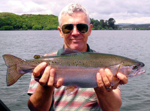 Proud fisherman: trout caught by proud fisherman, Lake Rotorua, New Zealand.  Don't think I'm experienced enough to clone out that corner successfully.  Have straightened and cropped somewhat... crop more?  Thankfully it was fairly calm on the water, boat not too rocky.  