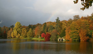 Lakeside with rainbow: Lakeside woodland in southwest England in autumn, with the end of a rainbow.