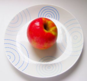 Apple on Plate: A red apple on a white plate with  blue pattern.