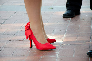 Red Pumps: Red high heel shoes on red tiles with mens shoes in the background